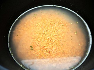 orange Linsen im schwarzen Topf nah