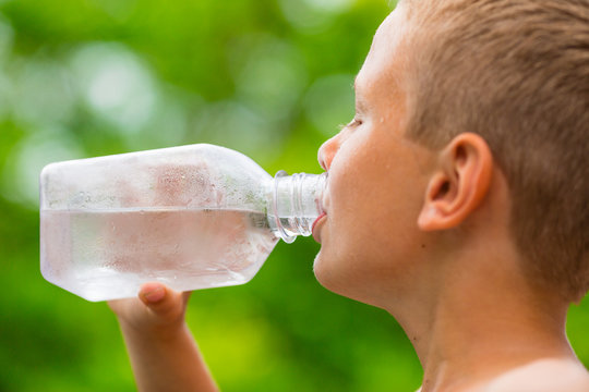 Boy drinking clean tap water from transparent plastic bottle