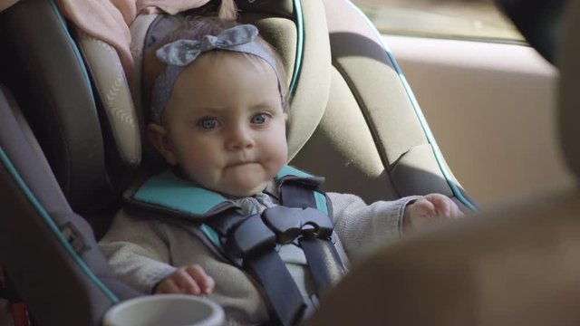 Adorable Smiley Baby Girl Sits In Her Car Seat, She Looks Out Window, And Around Car