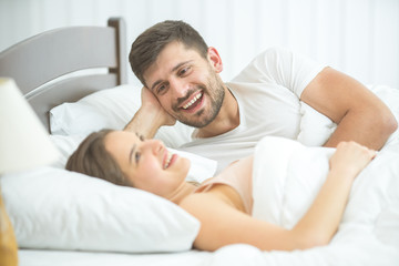 The smile woman and man lay on the comfortable bed