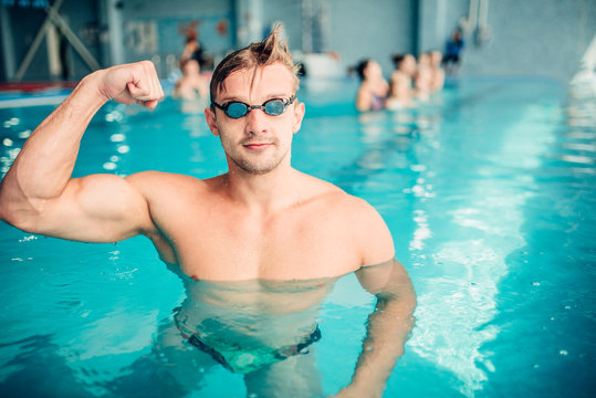 Athletic swimmer shows muscles, aqua sports