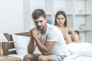 The depressed man sit near the woman in the bed