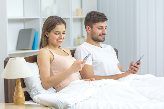 The young couple phone in the bed