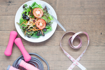 Sport equipments, fresh salad and measuring-tape in heart shape, Healthy lifestyle concept