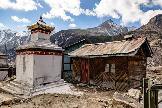 Tibetan stupa with rural wooden house with Black mountain with snow on the top is background at Thangu and Chopta valley in winter in Lachen. North Sikkim, India.
