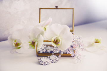 Obraz na płótnie Canvas Blooming white orchid flowers and glass box with handmade jewellery. Box handmade jewellery and earrings. Handmade accessories. 