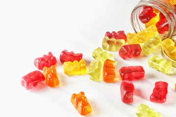 Gummies on isolated background poured from glass jars