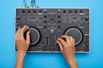 Female hands playing DJ mixer on blue background