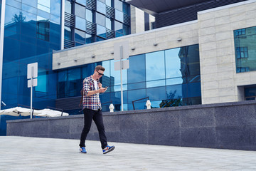 Stylish young man listens to music and enjoys city panorama