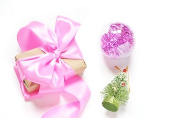 Flat lay winter holiday background/ Gift box with pink ribblon and bow, glossy ball and toy green fir tree. Merry Christmas and Happy New Year