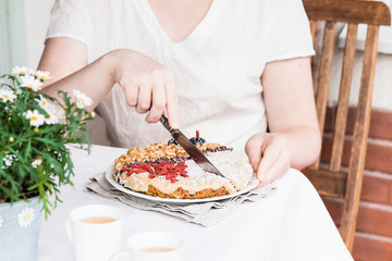 Obraz na płótnie Canvas Woman's hands cutting raw carrot cake with walnuts, goji berries
