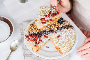 Woman's hands holding a piece of raw cake with goji