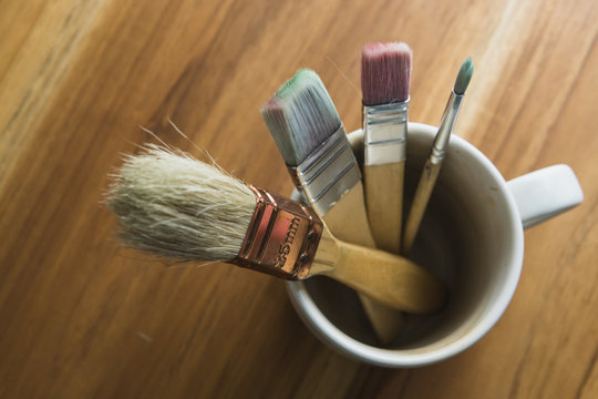 paint brushes in a coffee cup