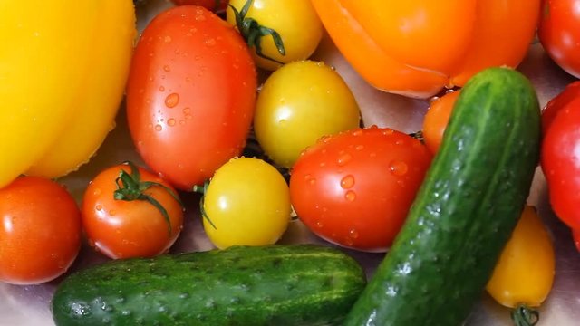 Water splashing on bell peppers in slow motion; shot on Phantom Flex Juicy fresh vegetables lie in the metal sink after washing. Green cucumber, okanzhevy pepper, yellow tomato. HD 25