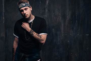 Dangerous tattooed gang member man stay on dark background. American gangster, dangerous people, urban style concept