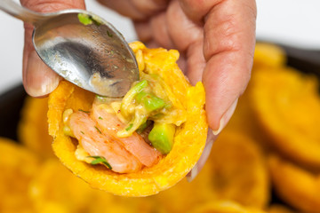 Close up of a woman filling a plantain cup with shrimp ceviche © anamejia18