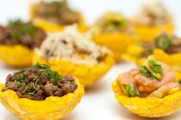 Plantain cups filled with different types of stuffing on white background