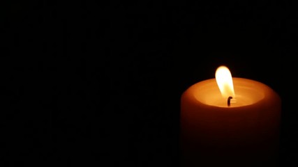 Closeup of burning candle isolated on black background