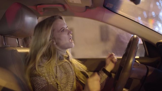 Profile Of Young Female Driver, She Dances And Sings In Car At Red Light, Light Turns Green And She Smiles At Her Passenger And Drives