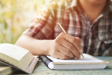 Fototapeta premium hand of people, student writing and note on notebook on wood table with copy space, in library, concept as education attempt and make effort to win, intend to improve knowledge for future life