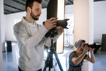 Creative photographers work in studio. Two people with cameras during the studio session. Creative...