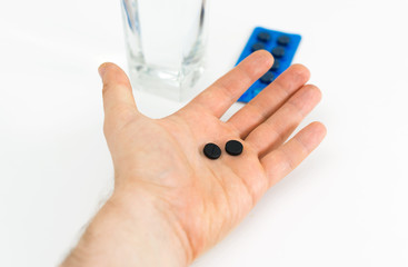 Man's hand holding activated carbon pills.