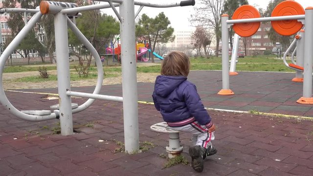4K Handsome blowzy kid spinning around on playground