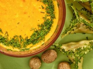 Pumpkin cream soup in a bowl with ravioli and nutmeg