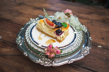 Piece of blueberry cheesecake on a decorated plate on wooden table.