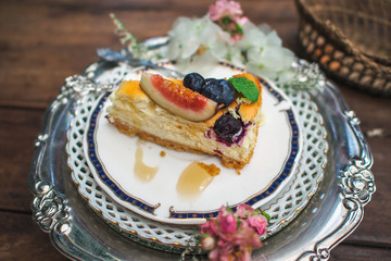 Piece of blueberry cheesecake on a decorated plate on wooden table.