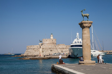 Statue Deer and hound and columns in Mandraki harbor. On background Santa Claus Fortress. Place...
