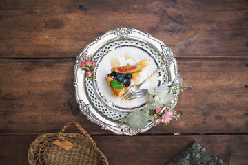 Piece of blueberry cheesecake on a decorated plate on wooden table.