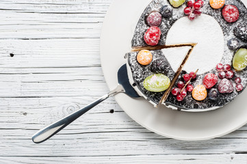 chocolate berry cake on plate over white wooden background