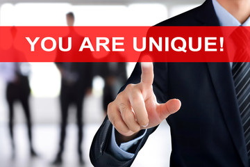 Businessman hand touching YOU ARE UNIQUE tab on virtual screen