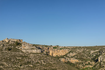 Fototapeta premium Beautiful green grass valley meadow with rock mountain in daylight summer with blue sky, Matera south Italy.