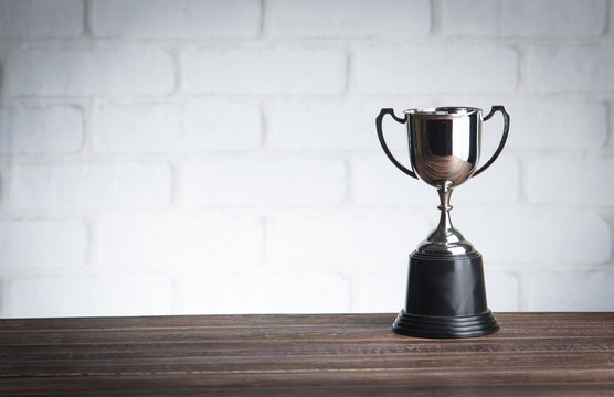 trophy over wooden table against white brick wall with Text Space