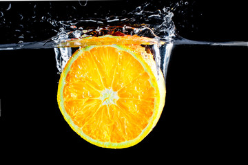Fototapeta na wymiar orange slice in water splash on black background