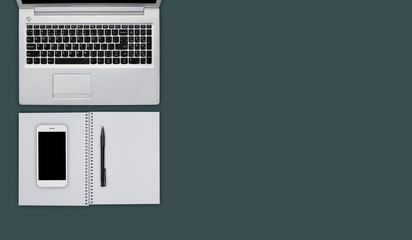 Flat layout of office supplies for work. Office desk with laptop, cell phone, notepad with blank sheets and pen. Necessary objects and gadgets for work in office. Desktop with copy space for text