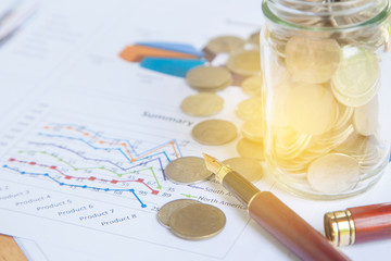 graph, chart and pen with stacks of coins