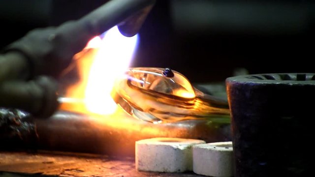 Close-up of tongue being added to glass snake as gaffer melts glass rod with blowtorch