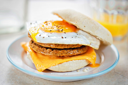 Meat free sausage flavour patties with cheese and egg on breakfast muffin 