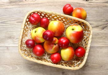 fresh ripe nectarines and plums in a basket on a wooden background