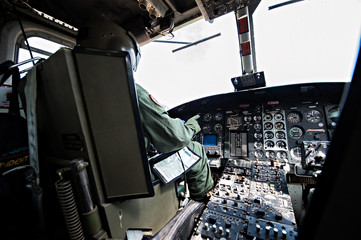 Cockpit interior details of Army helicopter with pilot and co pilot on board while flying over river. Pilot prepares to landing.