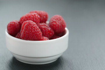 fresh raspberries in white bowl on slate board