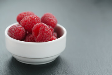 fresh raspberries in white bowl on slate board