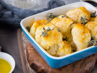Baked cauliflower with turmeric and marjoram on rustic background. Lunch with vegetables