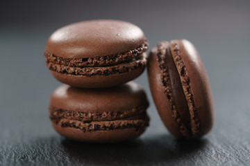 three chocolate macarons on slate board