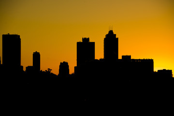 Fototapeta na wymiar Silhouette of city skyline against orange setting sun