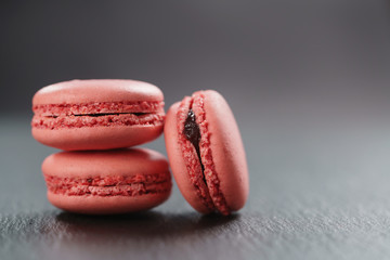 three raspberry macarons on slate board