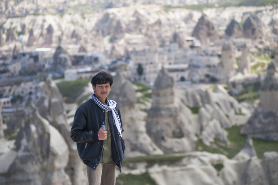 Young asian man tourist on the top of mountain at Cappadocia Anatolian plateau. Open air museum, Goreme national park.